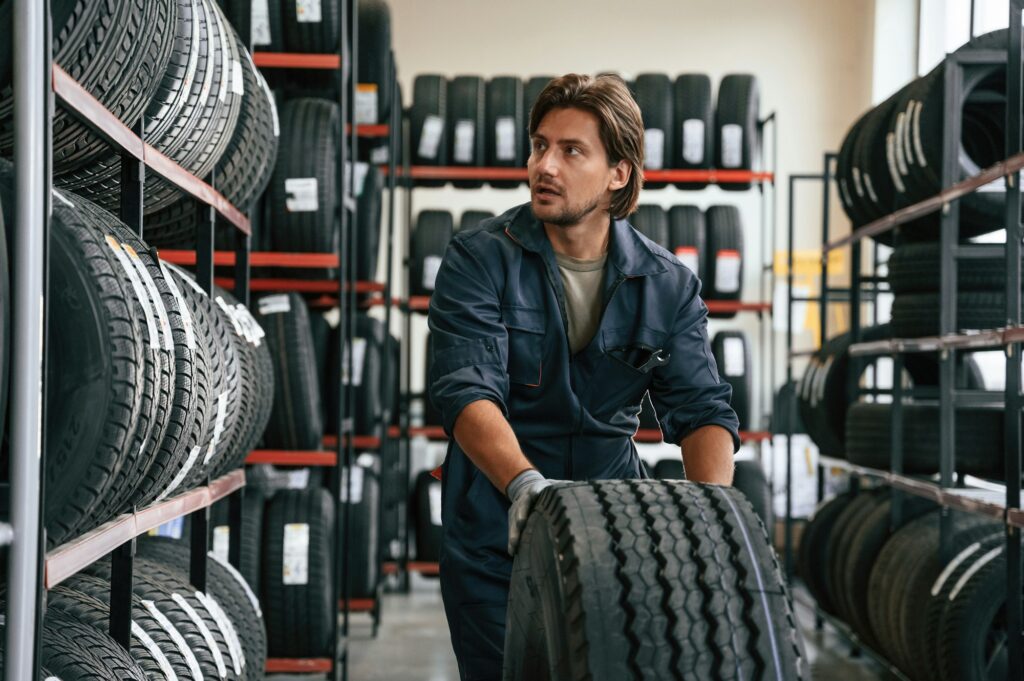 View from the front, guy with a tire. Man is in the tire fitting car service